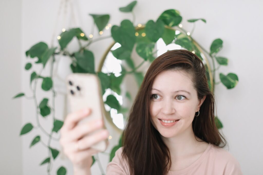 Portrait of a smiling young woman holding smartphone, making selfie or video chatting